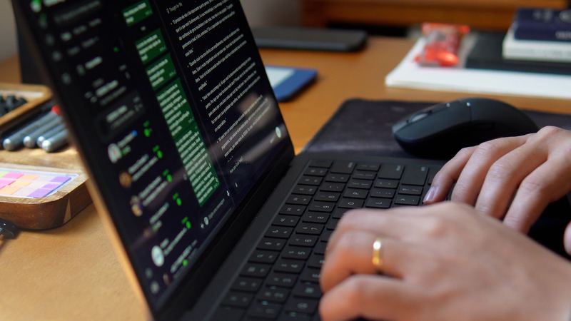 Mãos no teclado do notebook, com a tela de edição aberta