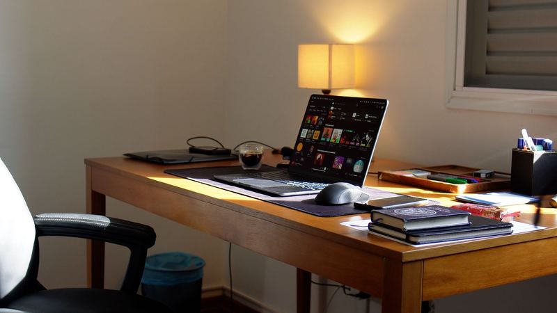 Mesa do escritório com notebook, luminária e livros