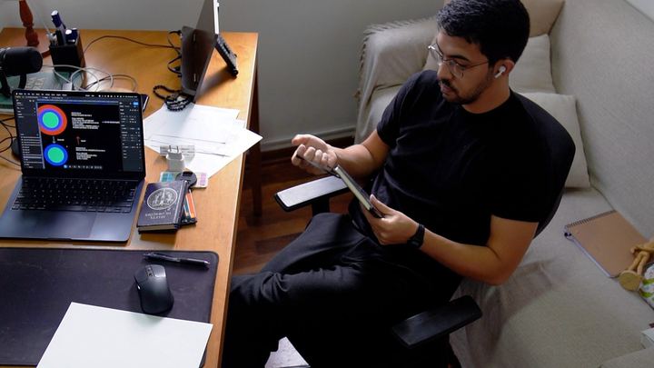 João Torres na mesa do escritório, revisando material no tablet